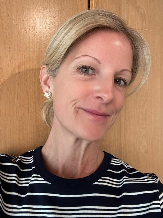 Woman with blonde hair and a striped shirt in front of a wooden door