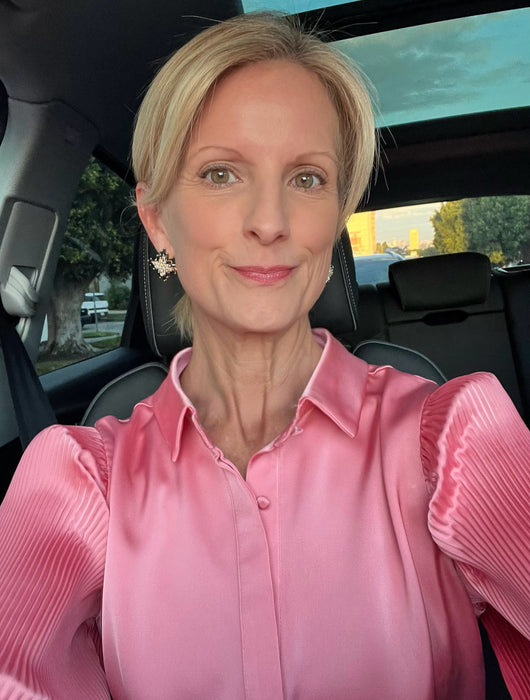 Woman in a pink shirt sitting inside a car with a scenic background