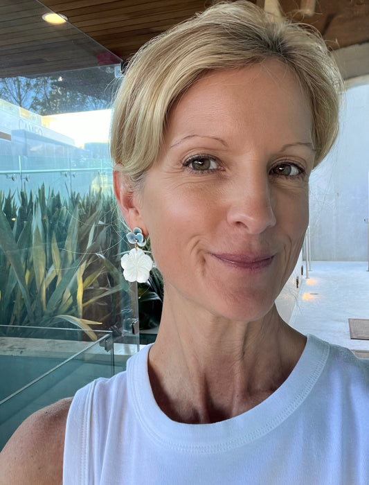 Woman wearing a white top with a blurred outdoor background