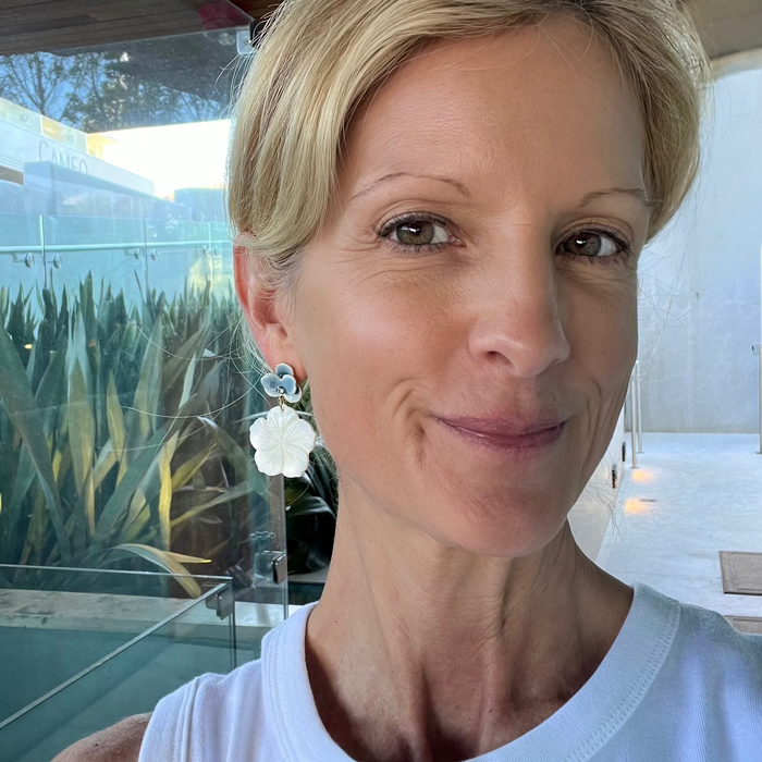 Woman wearing a white top with a blurred outdoor background