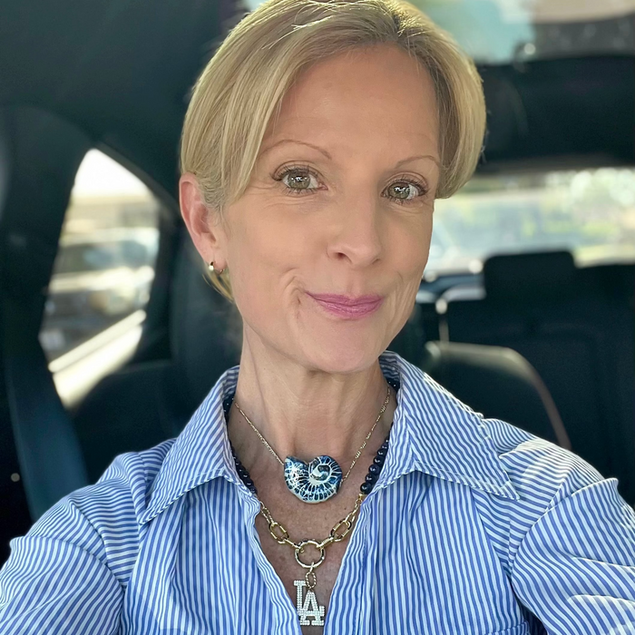 Woman wearing a blue striped shirt with visible jewelry, sitting inside a vehicle.