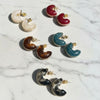Set of colorful crescent moon-shaped earrings on a marble surface