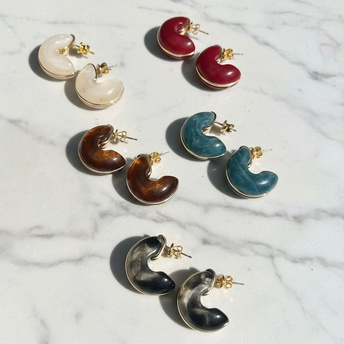 Set of colorful crescent moon-shaped earrings on a marble surface