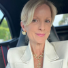 Woman in a white blazer with gold jewelry inside a vehicle