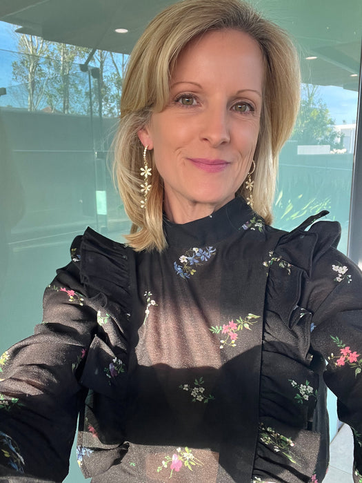 Woman wearing a black floral blouse with a blurred background