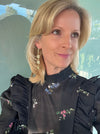 Woman wearing a black floral embroidered blouse indoors