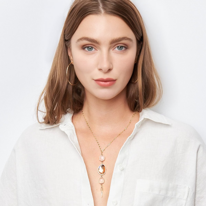 Woman wearing gold jewelry including a necklace, bracelet, and ring on a white background
