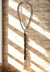 Necklace with beads and tassel on a textured wall