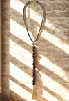 Necklace with beads and tassel on a textured wall