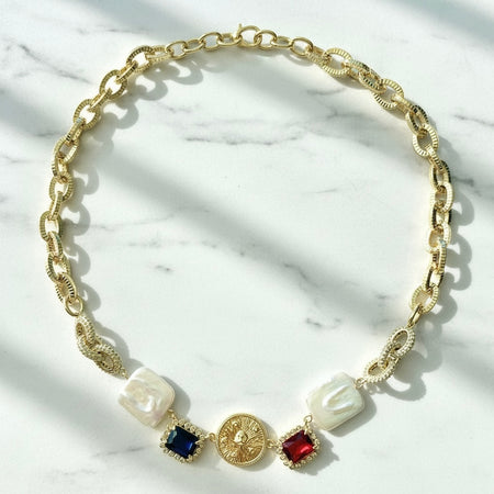 Gold chain necklace with decorative elements on a marble surface