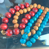 Three beaded bracelets in red, brown, and blue on a reflective surface.