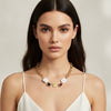 Woman wearing a gold necklace with colorful pendants against a neutral background