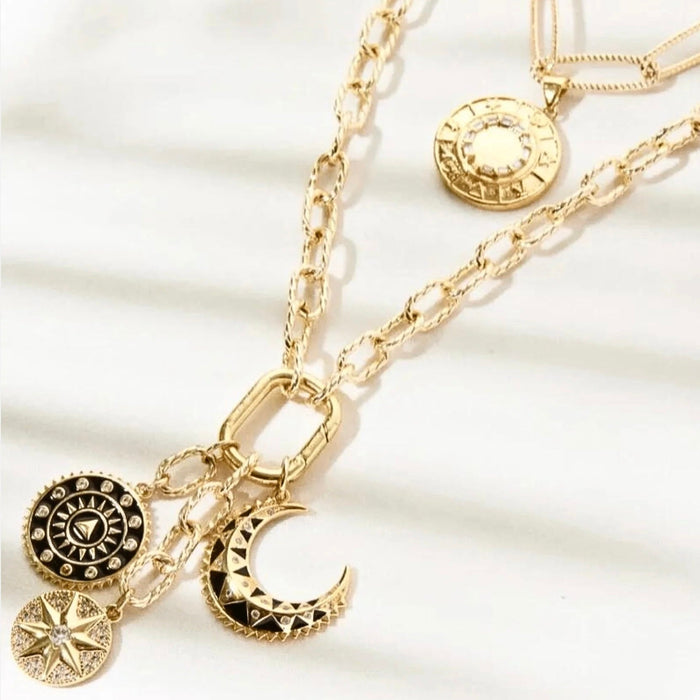 Gold necklace with various charms on a white background