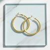 Gold hoop earrings on a white marble surface