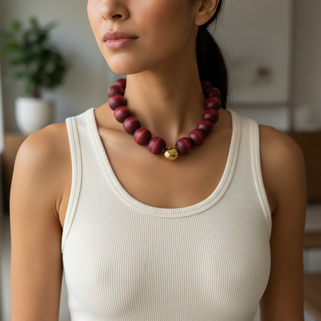 Woman wearing a red beaded necklace with a blurred indoor background
