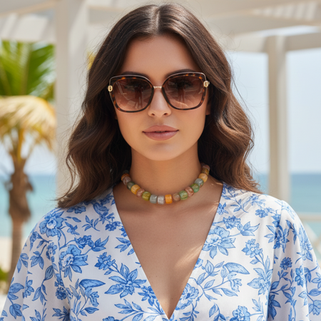 Woman wearing sunglasses and a floral dress with a beach background