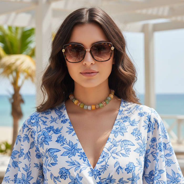 Woman wearing sunglasses and a floral dress with a beach background