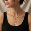 Gold chain necklace with pendant worn by a person against a neutral background