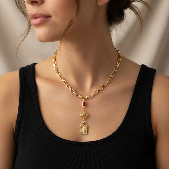Gold chain necklace with pendant worn by a person against a neutral background