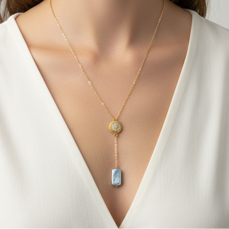 Gold necklace with a pendant on a person wearing a white top