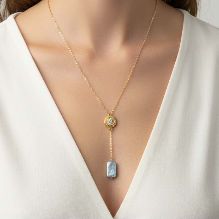 Gold necklace with a pendant on a person wearing a white top