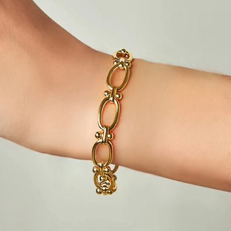 A gold-filled intricate oval link chain bracelet worn on a wrist.