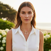 Woman wearing a gold necklace outdoors with greenery in the background