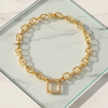 Gold chain bracelet with square links on a marble surface