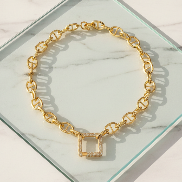 Gold chain bracelet with square links on a marble surface