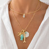 A close-up of a model wearing a layered gold necklace set. The top layer is a delicate gold chain with a small teardrop crystal pendant.