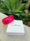 Pink bracelet on a white box with 'CF The Christy F Collection' branding, set against a green plant background.