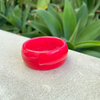 Pink bracelet on a textured surface with green foliage in the background