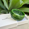 Green bracelet on a white box with 'CF' branding, set against a green leafy background.