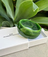 Green bracelet on a white box with 'CF' branding, set against a green leafy background.
