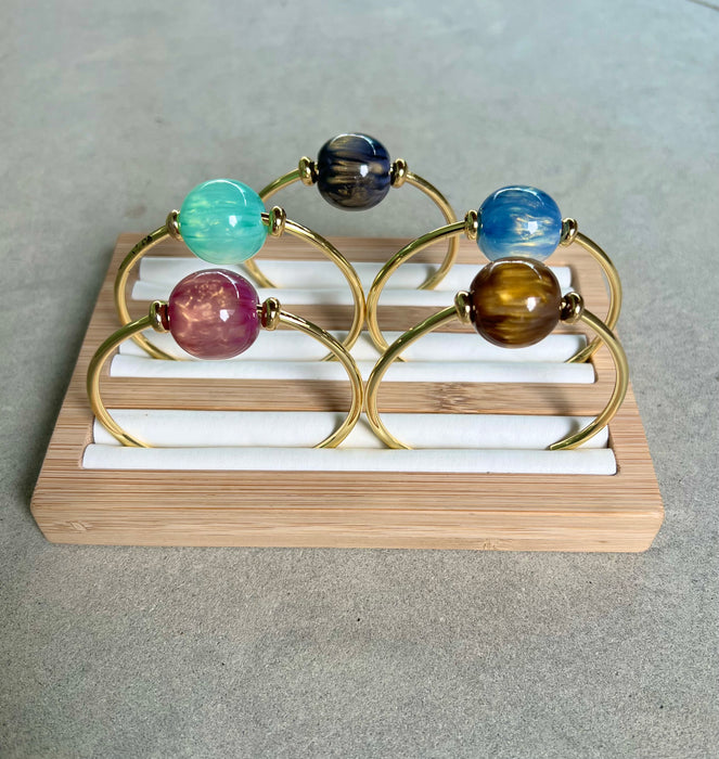 Decorative bracelet with colorful beads on a wooden stand against a neutral background