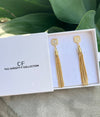 Gold tassel earrings in a box with 'The Christy F Collection' branding.