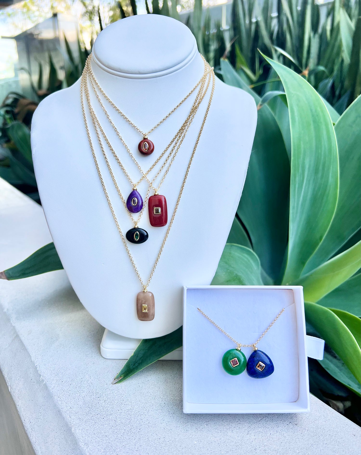 Necklace set on a mannequin bust with green foliage in the background