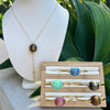 Necklace on a mannequin bust with a wooden display of rings featuring gemstones.