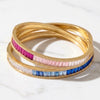 two ombre bangles one in blue and one in pink both with cubic zirconia baguettes on a marble background.