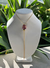 Necklace with a purple gemstone on a mannequin bust against a green leafy background