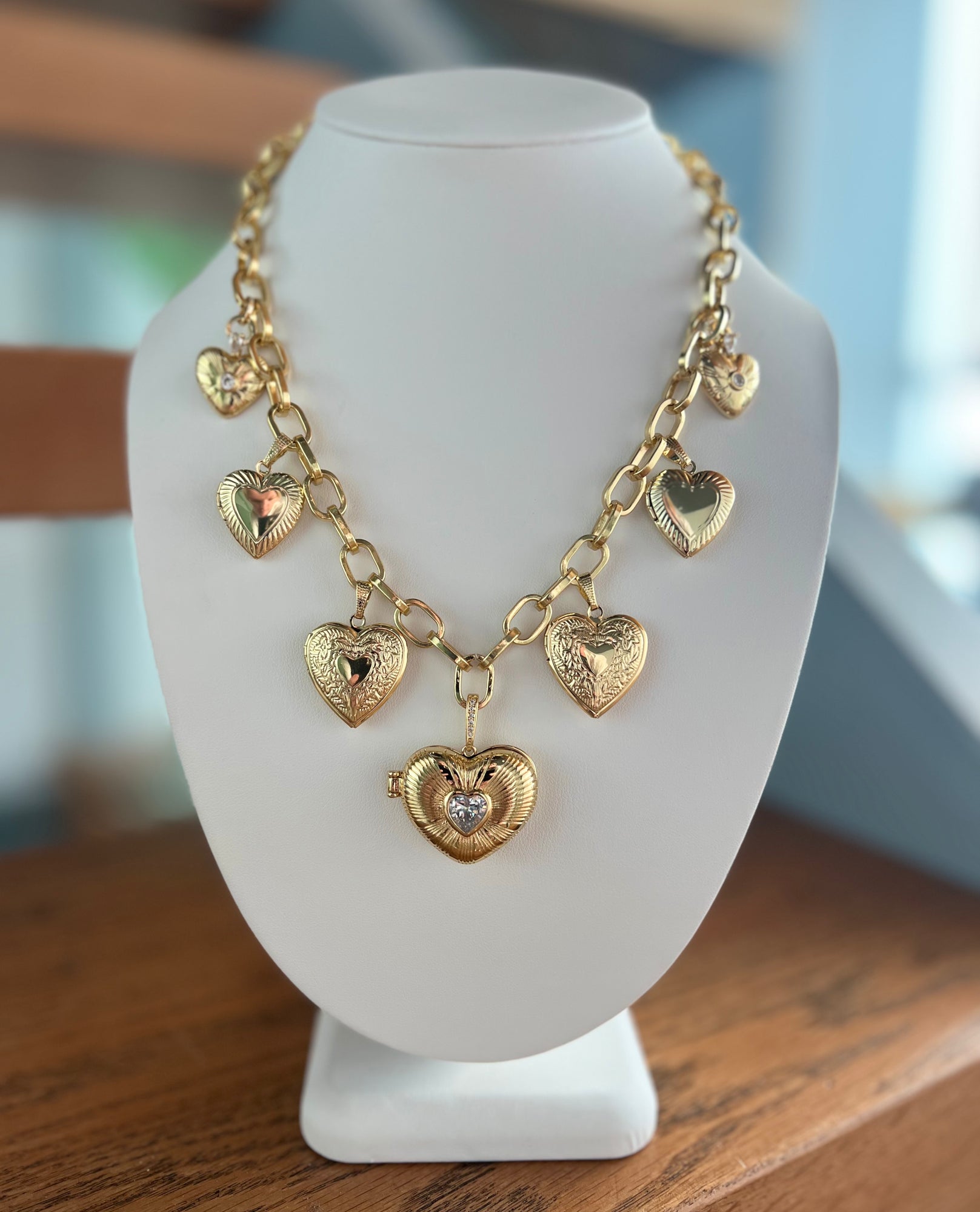 Gold heart-shaped necklace on a white mannequin bust.
