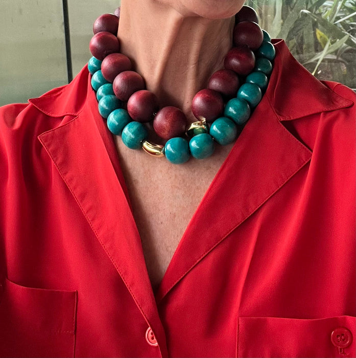 Person wearing a red jacket with a large turquoise and burgundy beaded necklace.