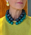 Person wearing a blue and green beaded necklace with a gold clasp.