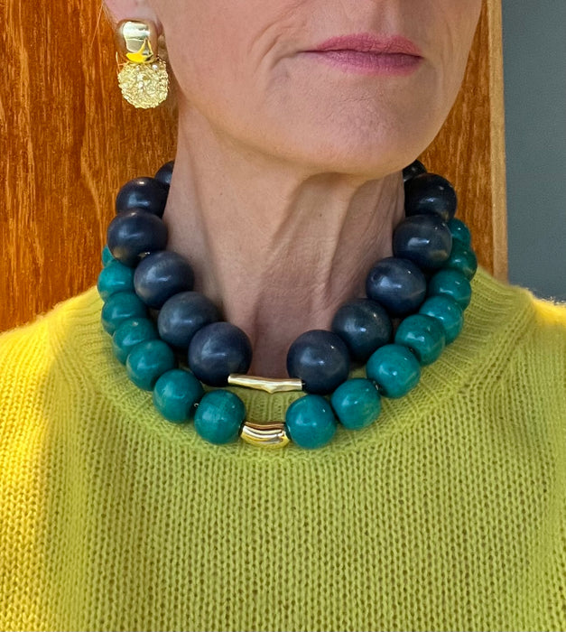 Person wearing a blue and green beaded necklace with a gold clasp.