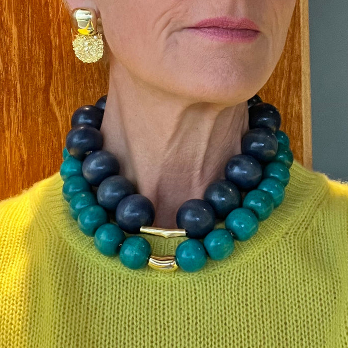Person wearing a blue and green beaded necklace with a gold clasp.