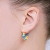 Close-up of an ear wearing colorful hoop earrings with a blurred background