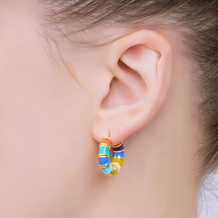 Close-up of an ear wearing colorful hoop earrings with a blurred background