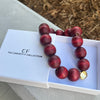 Wooden beaded necklace with a gold accent on a white box labeled 'The Christy F Collection'.