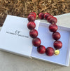Red beaded necklace with a gold clasp on a white box labeled 'The Christy F. Collection'.