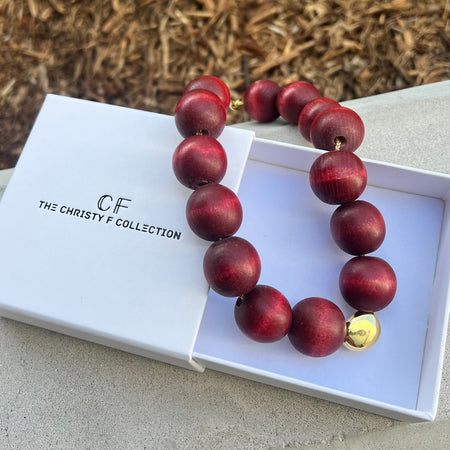 Red beaded necklace with a gold clasp on a white box labeled 'The Christy F. Collection'.